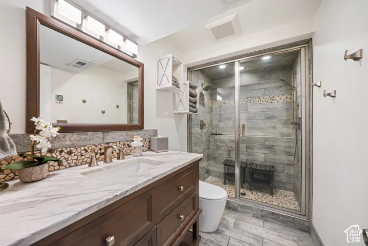 Custom steam shower, lighted bidet smart toilets, vanity with a white marble-finish countertop, integrated sink, and bronze-finish faucet