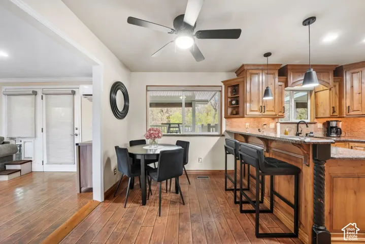 Wood-finish flooring throughout, kitchen with wood cabinetry, integrated bar seating, and pendant lighting