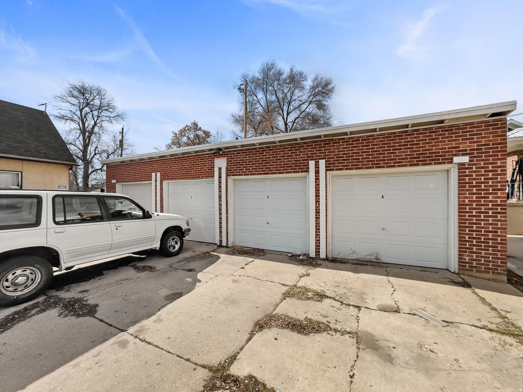 Red brick exterior featuring multiple garage doors and a concrete drive