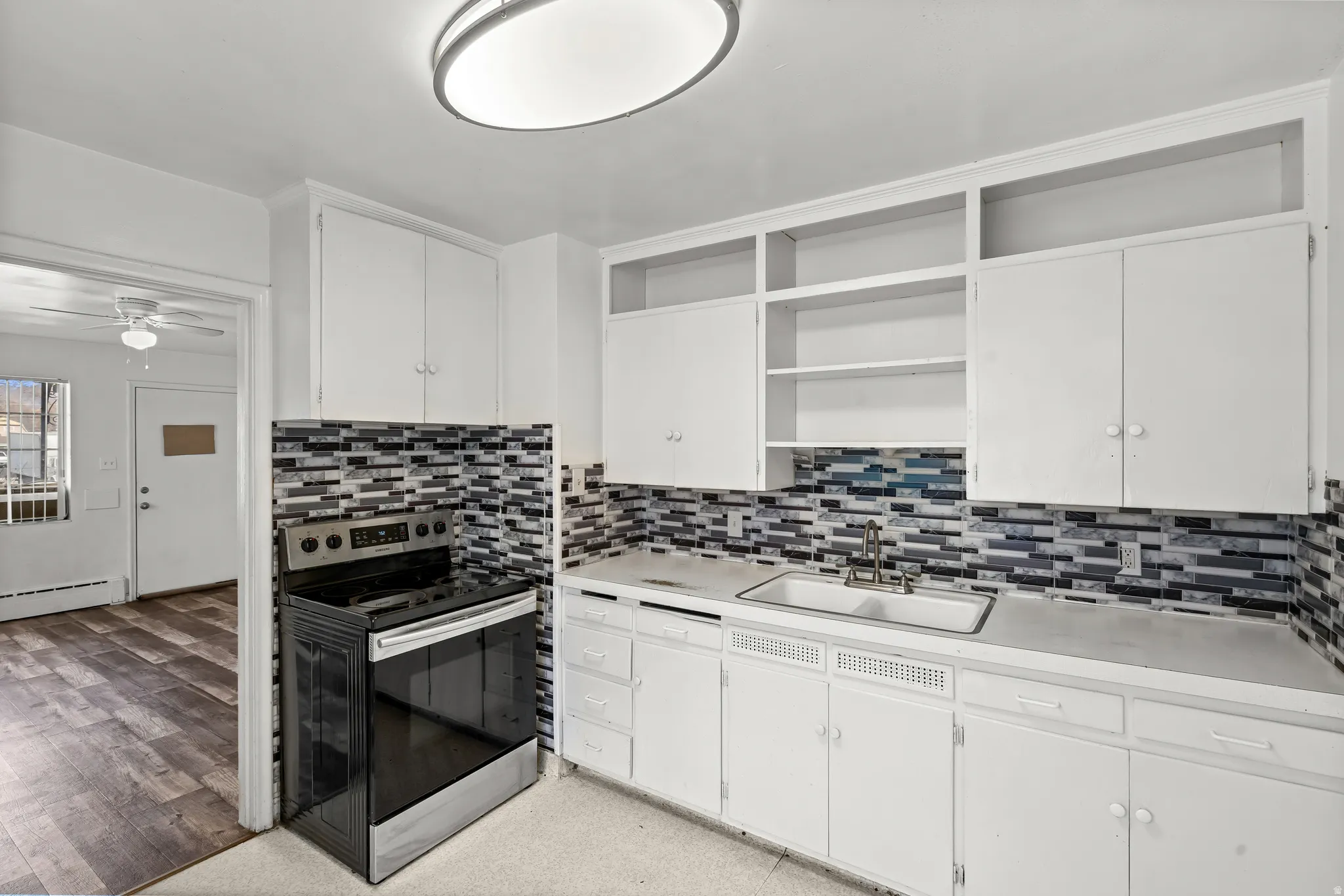 Kitchen featuring white cabinetry, a stainless steel range, a mosaic tile backsplash, and a double basin sink