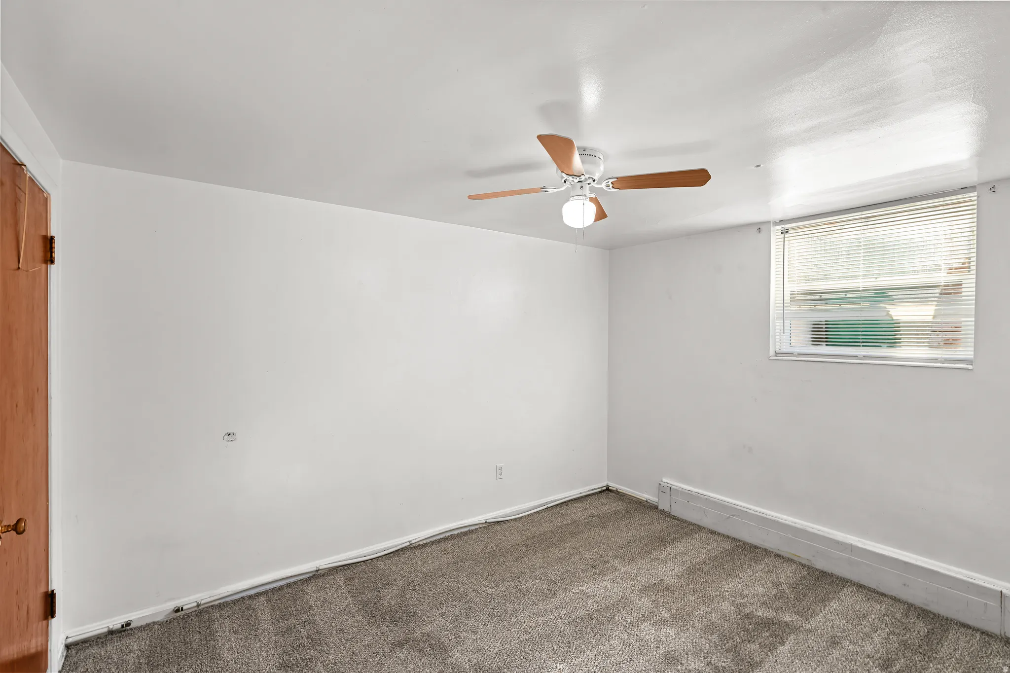 Wall-to-wall carpeting, ceiling fan with light fixture, wood-finish door, and window with blinds