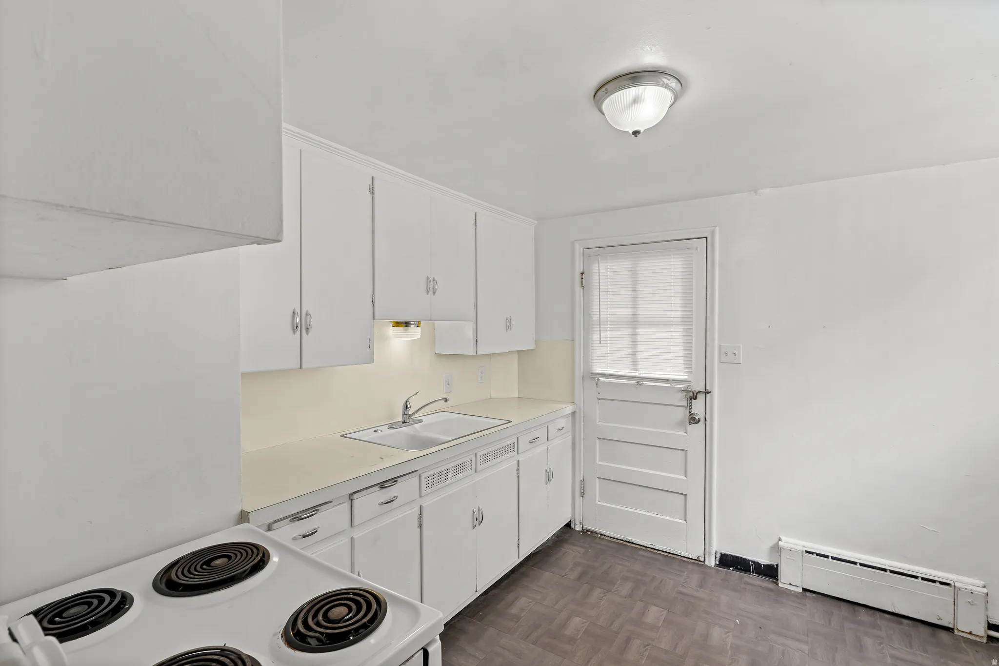 White cabinetry with brushed nickel hardware, dual basin sink, integrated countertop, and wood-finish flooring