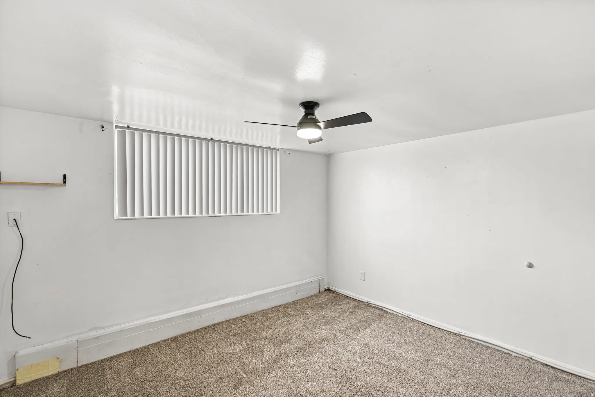 Neutral wall color, wall-to-wall carpeting, and a ceiling fan with light fixture