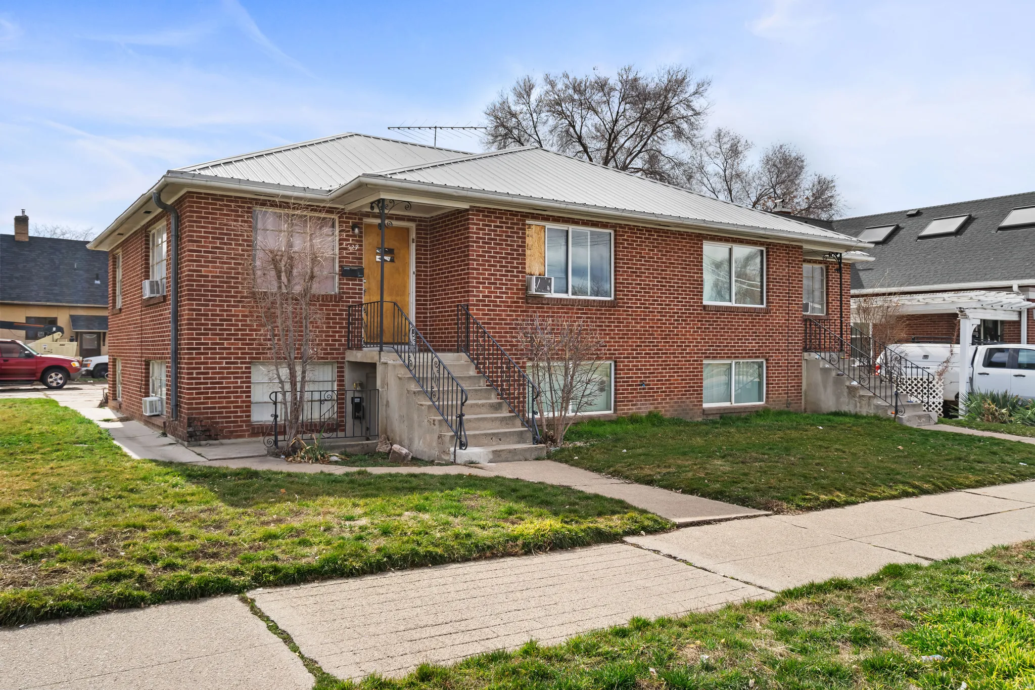 Red brick exterior with white trim, metal roof, and concrete walkways