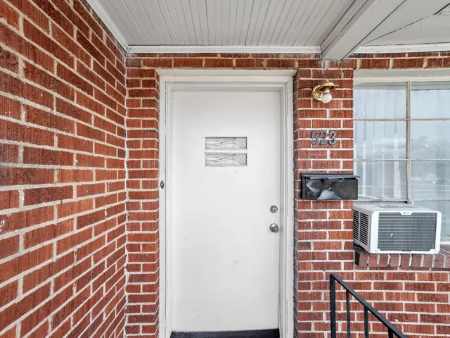 Red brick exterior featuring a white entry door with textured glass inserts