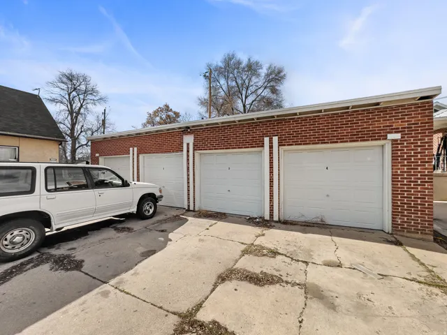 Red brick exterior featuring multiple garage doors and a concrete drive