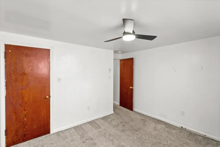 Neutral tone wall paint, wood-finish doors, and a ceiling fan with integrated lighting
