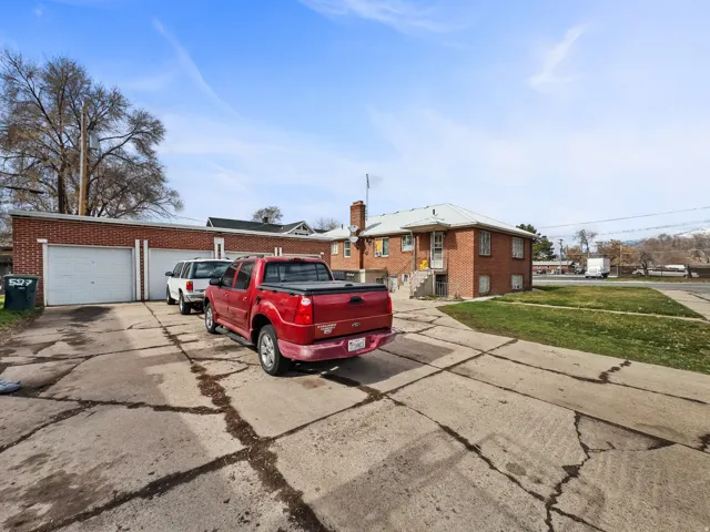 Brick exterior residence with a multi-car garage, mature trees, and a paved driveway
