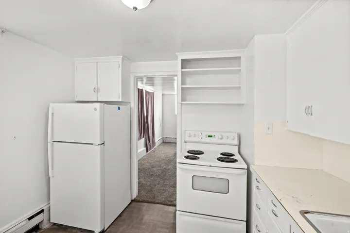 White painted cabinetry, built-in shelving, white appliances, and a single-basin sink