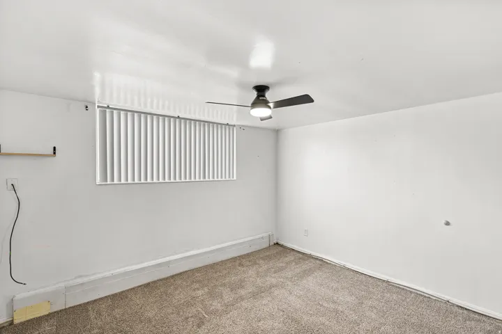 Neutral wall color, wall-to-wall carpeting, and a ceiling fan with light fixture
