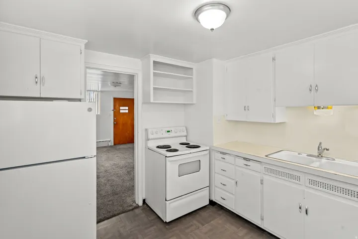 Kitchen featuring white cabinetry, a double basin sink, and a white electric range