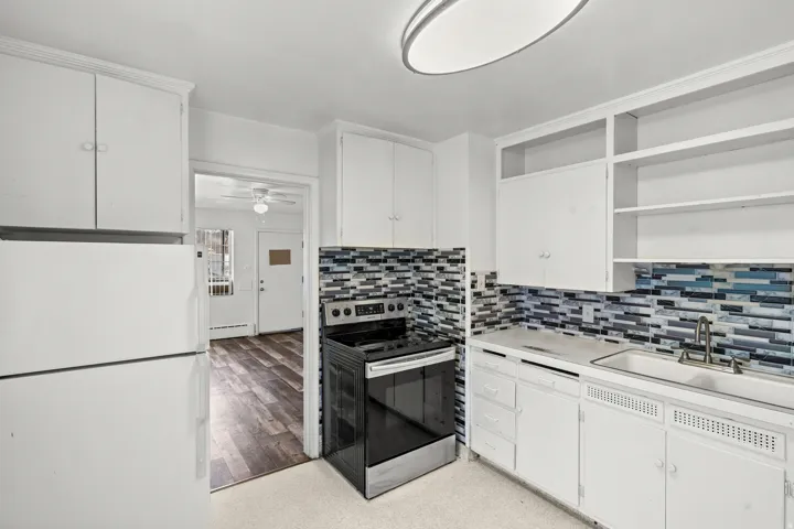 Kitchen featuring white cabinetry, a mosaic tile backsplash, a stainless steel electric range, and a white refrigerator