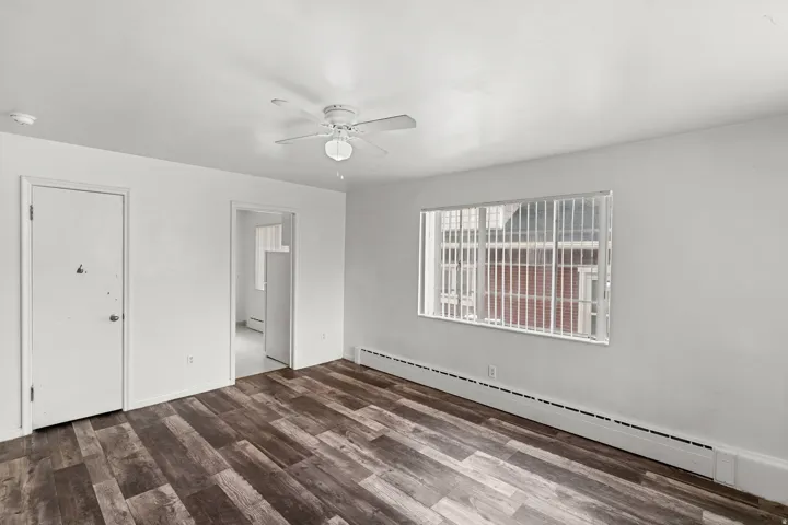 Wood-finish flooring, white walls, and a ceiling fan with integrated lighting