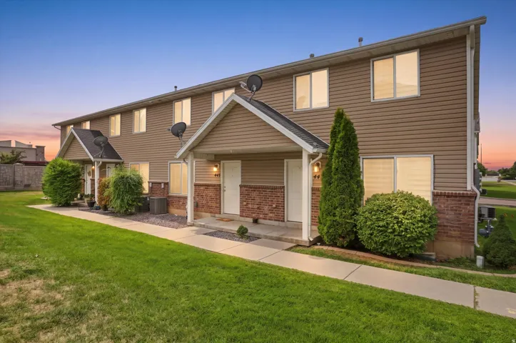 Brown siding exterior with brick accents, covered entryways, manicured landscaping, and a concrete pathway