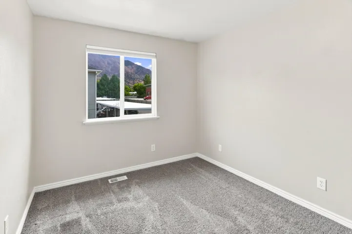 Neutral wall paint, gray carpet flooring, and a double-pane window with mountain scenery