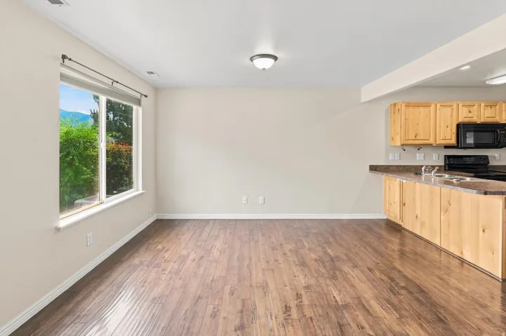 Wood-finish flooring, recessed ceiling lighting, kitchen with light wood cabinetry, black appliances, and a double basin sink