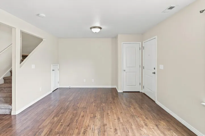 Wood-finish flooring throughout, neutral wall paint, white trim, and a flush mount ceiling light fixture