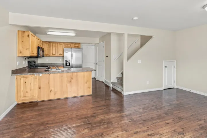 Kitchen with wood cabinetry, stainless steel appliances, and dark countertops