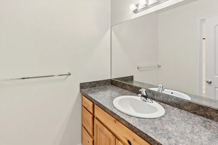 Vanity featuring a laminate countertop, integrated sink, and wood-finish cabinetry