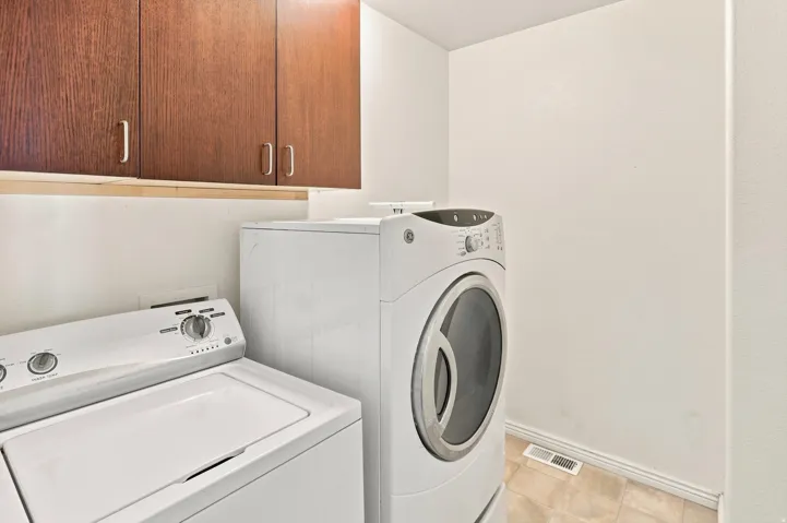 Laundry area featuring overhead cabinetry, a top-load washer, and a front-load dryer