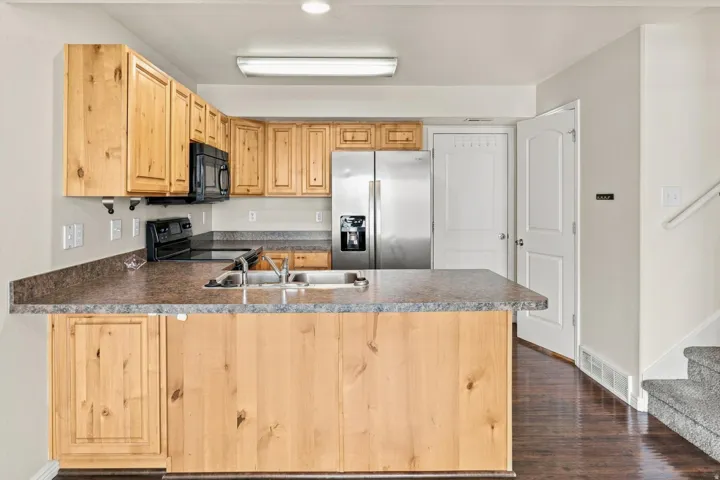Kitchen with wood-finish cabinetry, stainless steel appliances, and dark countertops