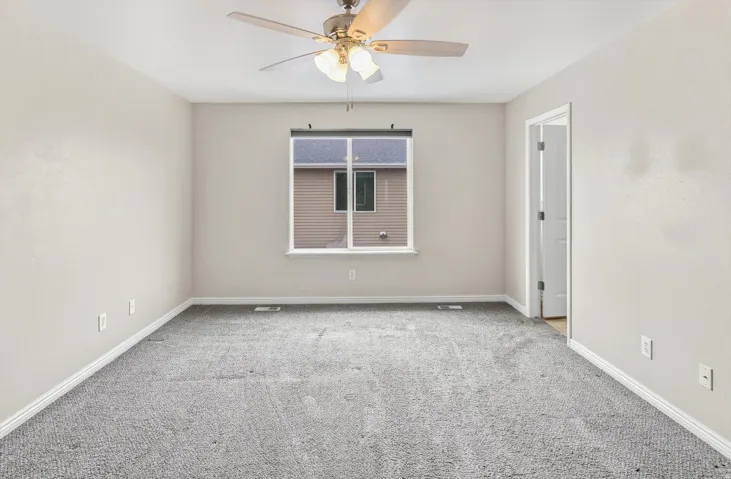 Ceiling fan with integrated lighting, neutral wall paint, white trim, carpeted flooring, and a single window