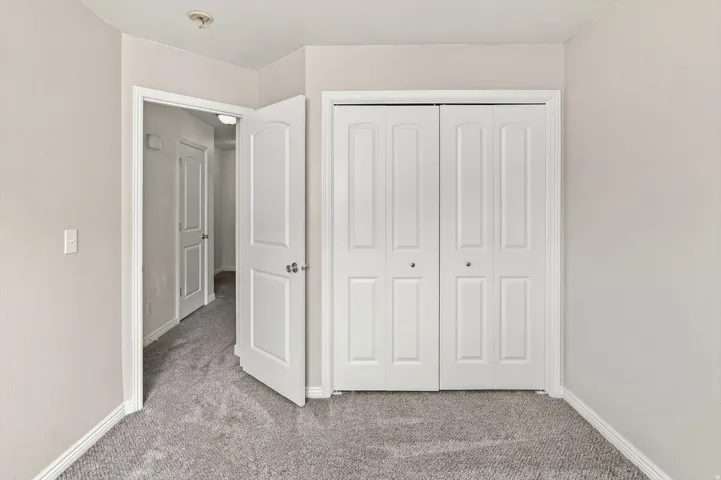 Neutral tone wall paint, carpet flooring, white trim, and white bi-fold closet doors
