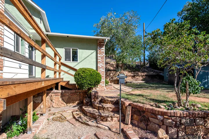 Wood-toned deck with railings, stone retaining wall, and stone steps