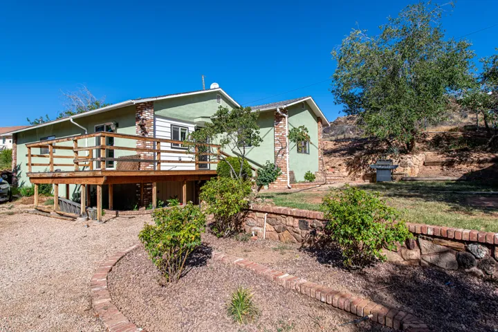 Spacious outdoor deck with wood railings, gravel ground cover, and brick-lined landscaping