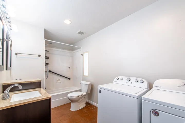 Bathroom featuring a vanity with a light-toned countertop, a built-in shower/tub combination, and tiled flooring
