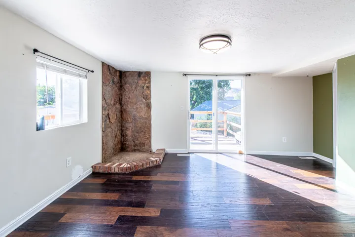 Stone fireplace with a brick hearth, wood-finish flooring, and a sliding glass door