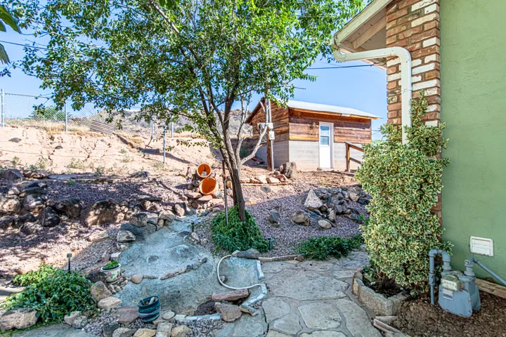 Flagstone path with rock-lined landscaping, featuring a decorative dry creek bed and a mature tree