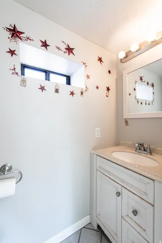 Vanity with an integrated sink and light-toned countertop, wall-mounted mirror, and overhead vanity lighting