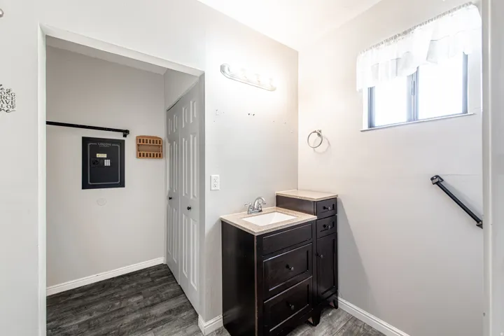 Vanity with integrated sink, wood-finish flooring, and window