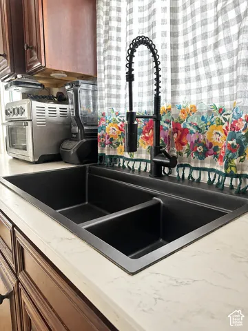 Double basin undermount sink with a matte black high-arc faucet, set within a light-toned countertop with subtle veining