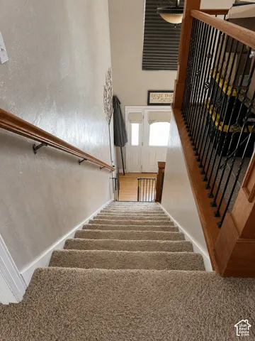 Carpeted staircase with wood-finish handrails and black metal balusters