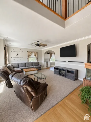 Carpeted living area with a vaulted ceiling, ceiling fan, and decorative archway