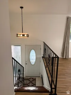 Entryway featuring a white door with an oval glass insert, a contemporary pendant light fixture, and black iron railings