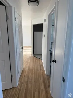 Hallway with wood-finish flooring, white paneled doors, and a flush mount ceiling light fixture