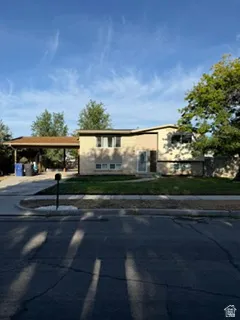 Split-level residence featuring a carport, mature trees, and a landscaped front yard with a walkway