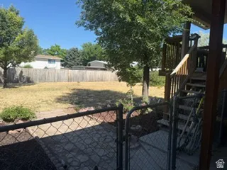 Expansive backyard featuring a wood privacy fence, mature trees, and a multi-level wood deck with stairs and railing