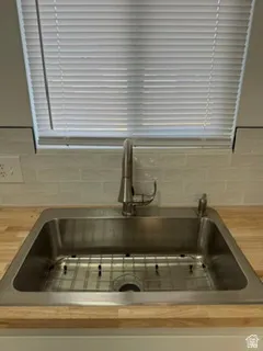 Stainless steel sink with a high-arch faucet, butcher block countertop, and subway tile backsplash