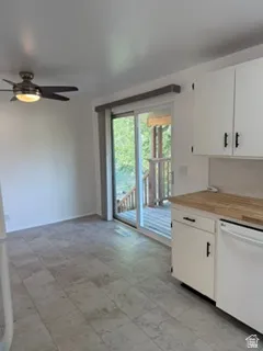 White cabinetry with dark hardware, butcher block countertops, white appliances, and a sliding glass door