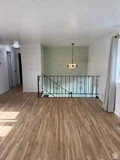 Wood-finish flooring throughout, wrought iron railing, and a contemporary pendant light fixture