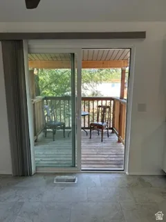 Sliding glass door opening to an outdoor deck with wood railings, featuring a tile floor