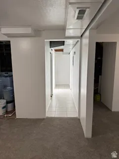 Carpeted flooring, white painted walls, and a tiled hallway