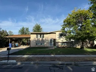 Two-story exterior with a covered carport, expansive front lawn, and mature trees