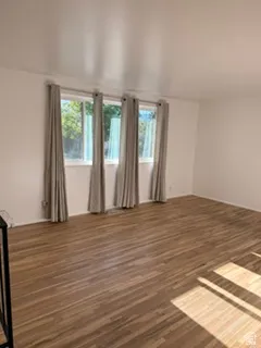 Expansive room featuring wood-finish flooring, white walls, and multiple windows