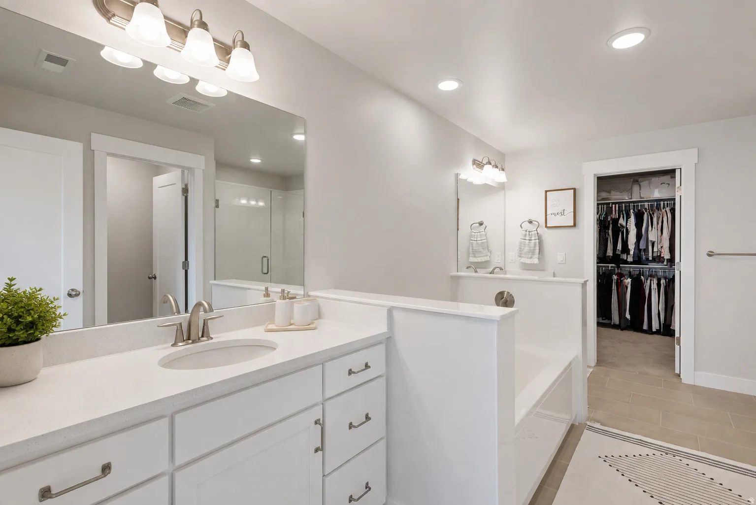 White vanity with an undermount sink, a rectangular mirror, and a wall-mounted light fixture