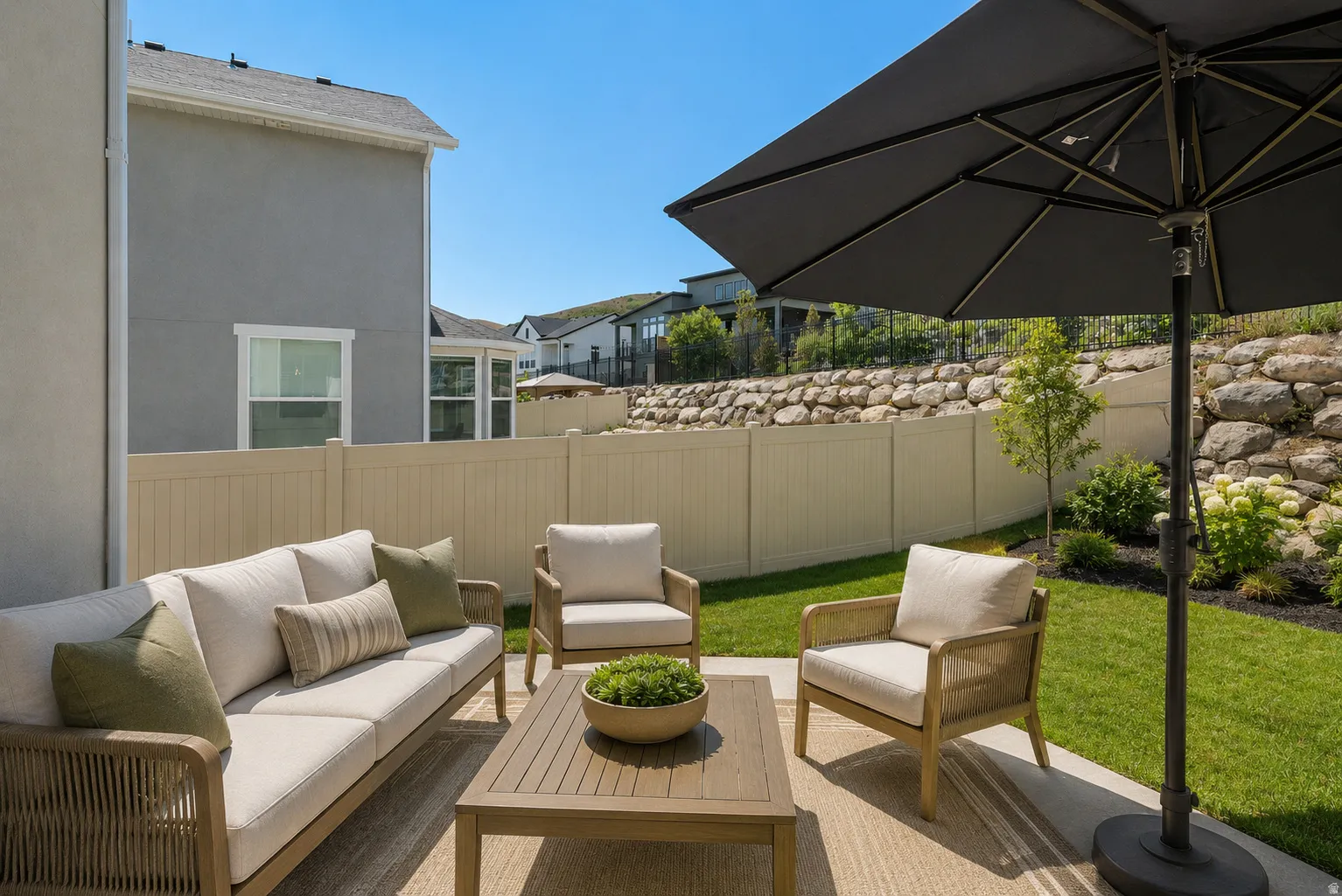 Outdoor patio with concrete flooring, privacy fencing, and a retaining wall featuring natural stone